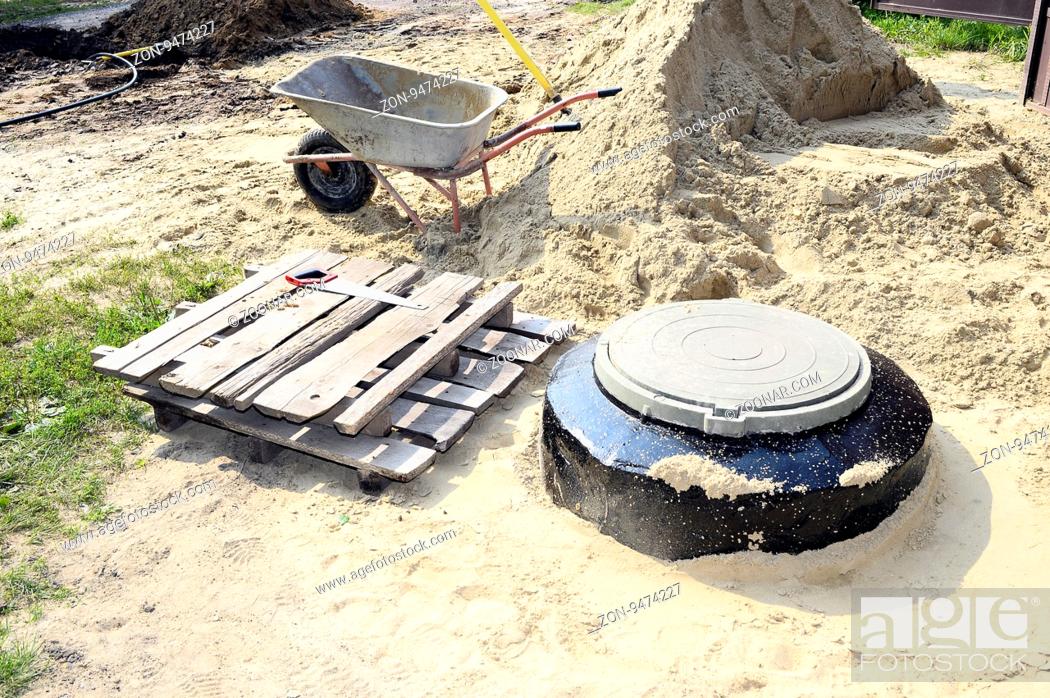 Stock Photo: Construction site with new armed manholes, cart, sand and equipment.