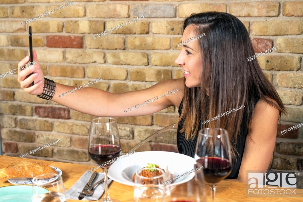 Stock Photo: Beautiful Young woman is taking a selfie photograph while eating in restaurant. High quality photo.