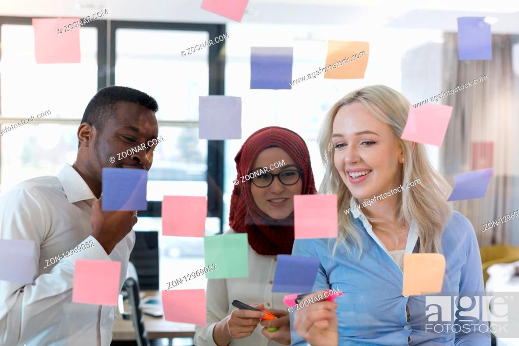 Stock Photo: young creative startup business people on meeting at modern office making plans and projects with post stickers on glass.