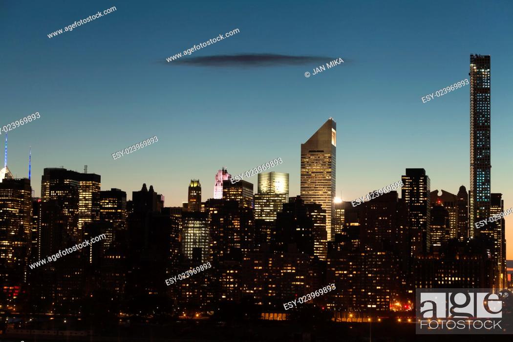 Stock Photo: Midtown Manhattan cityscape with clear sky and one dark flat cloud during twilight in New York City.