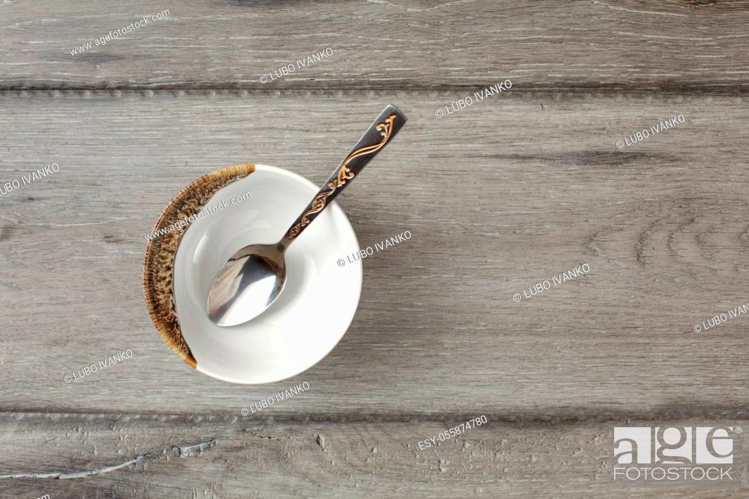 Stock Photo: Table top view on small empty porcelain bowl with silver decorated spoon, placed on gray wood desk.