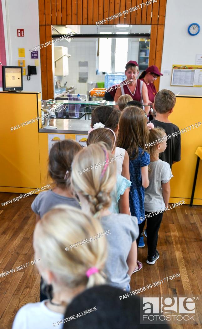 Stock Photo: 07 August 2019, Berlin: Before lunch, pupils stand in the cafeteria in the primary school on the Wuhlheide in the queue in front of the food counter.