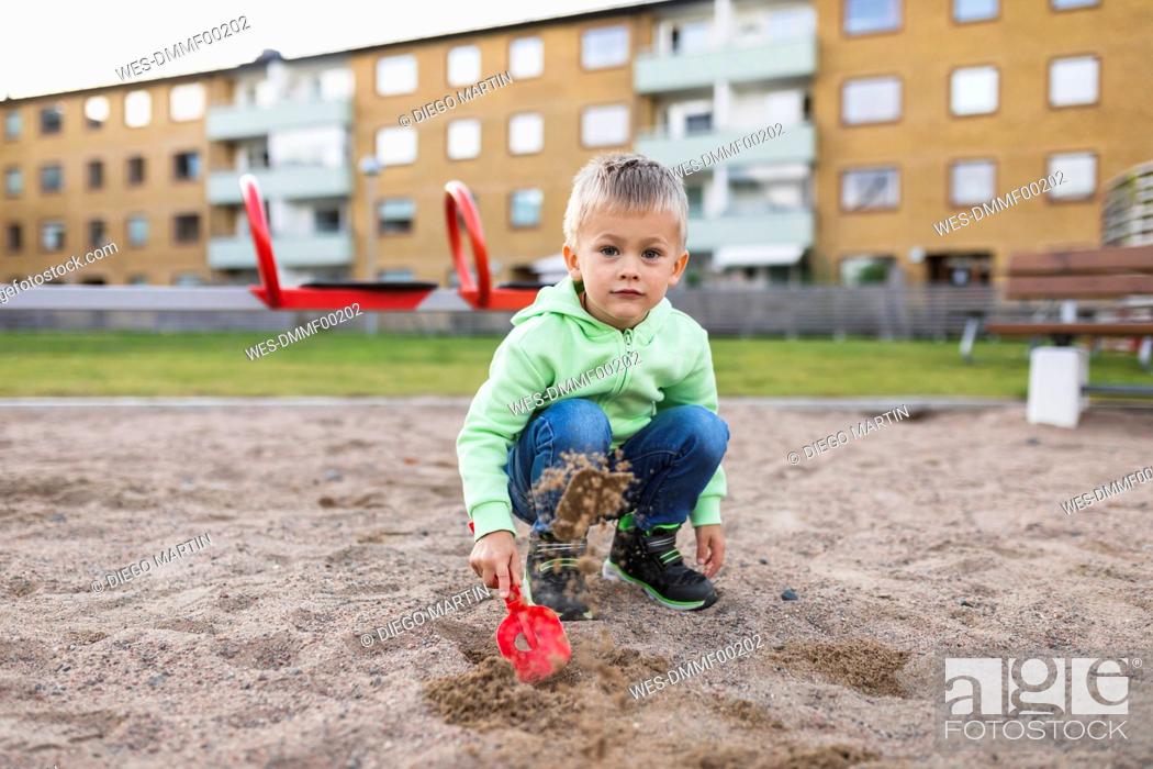 Stock Photo: Cute boy splashing sand with shovel in playground.