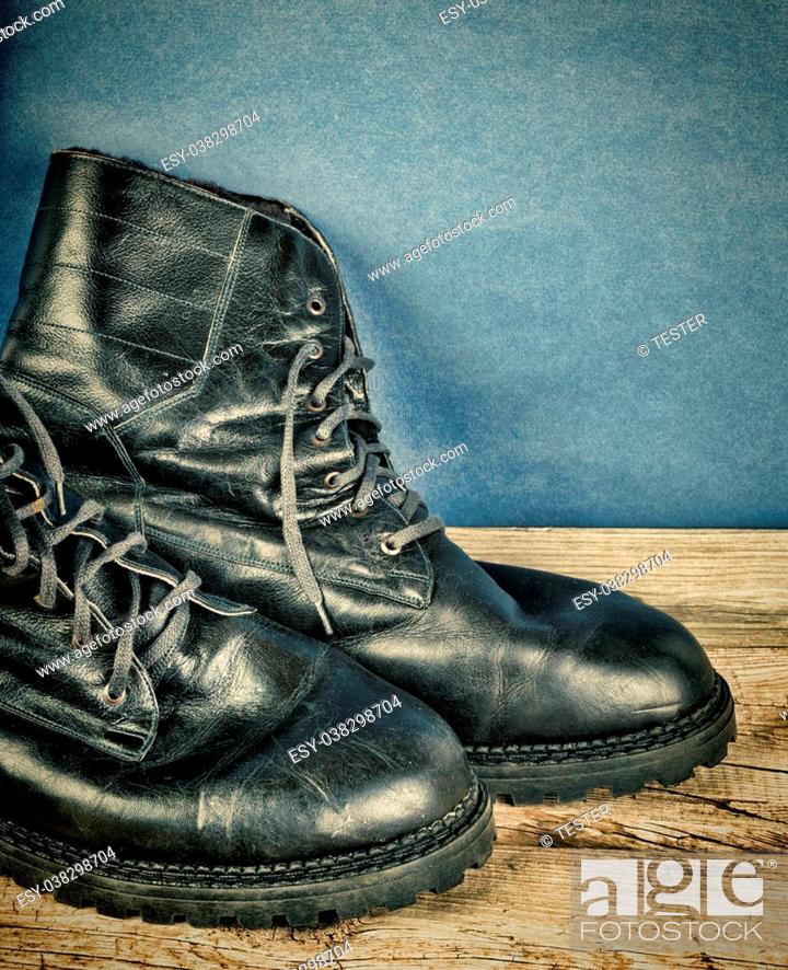 Stock Photo: Black army boots against the wall. Toned.
