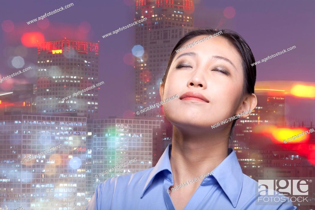 Stock Photo: Portrait of young smiling businesswoman, cityscape of Beijing, eyes closed.