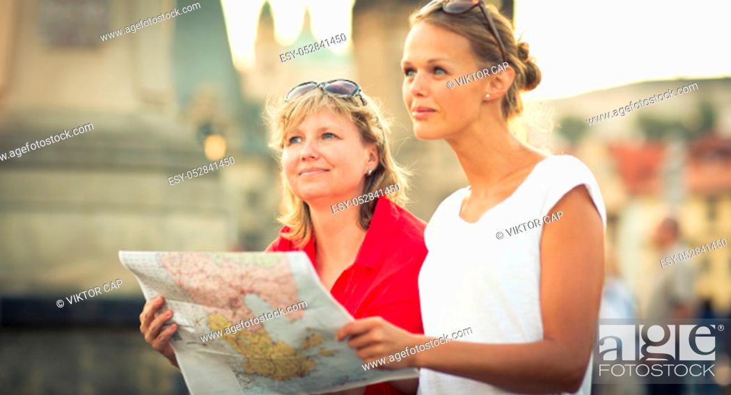 Photo de stock: Mother and daughter traveling - two female tourists studying a map, discovering a new city.