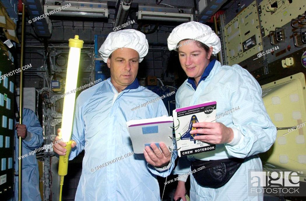 Stock Photo: 06/08/2002 -- STS-107 Mission Specialists Ilan Ramon, with the Israeli Space Agency, holds a light wand while he and Laurel Clark check out data for equipment.