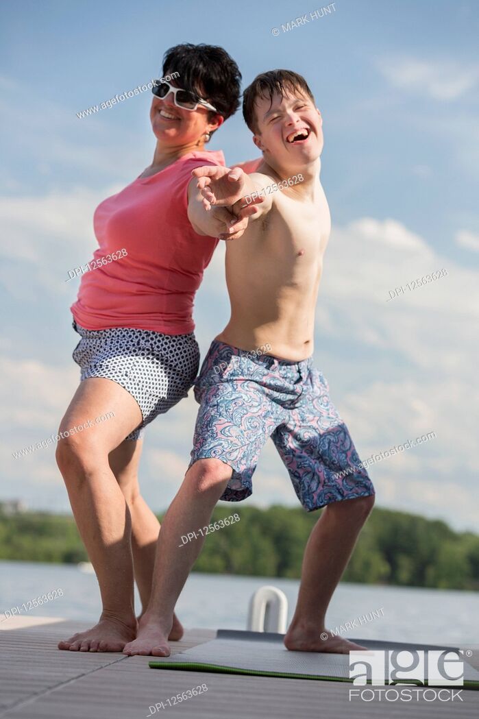 Stock Photo: Young man with Down Syndrome exercising on a dock with his friend.