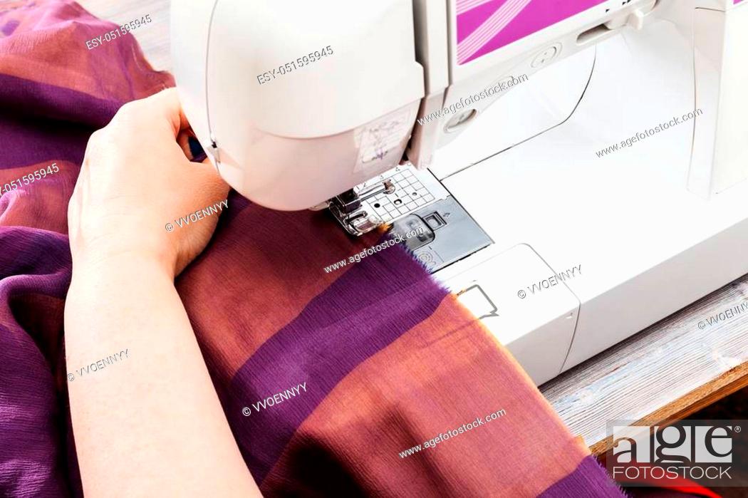 Stock Photo: workshop on sewing a patchwork scarf - designer hems strips of fabrics for the future silk shawl with sewing machine.