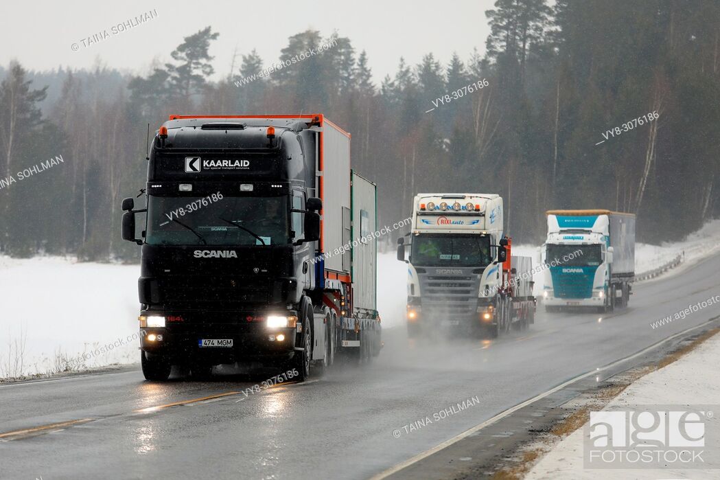 Stock Photo: Two special transport semi trucks and a cargo semi trailer move along highway in South of Finland in challenging winter weather conditions.