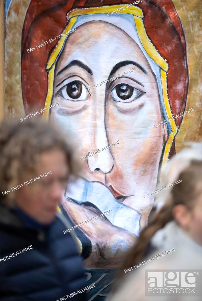 Stock Photo: 11 May 2019, North Rhine-Westphalia, Münster: A banner shows Mary, the Mother of God, with a plaster on her mouth during an open-air service.