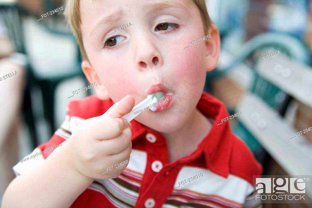 Stock Photo: Young boy eating ice cream with spoon.