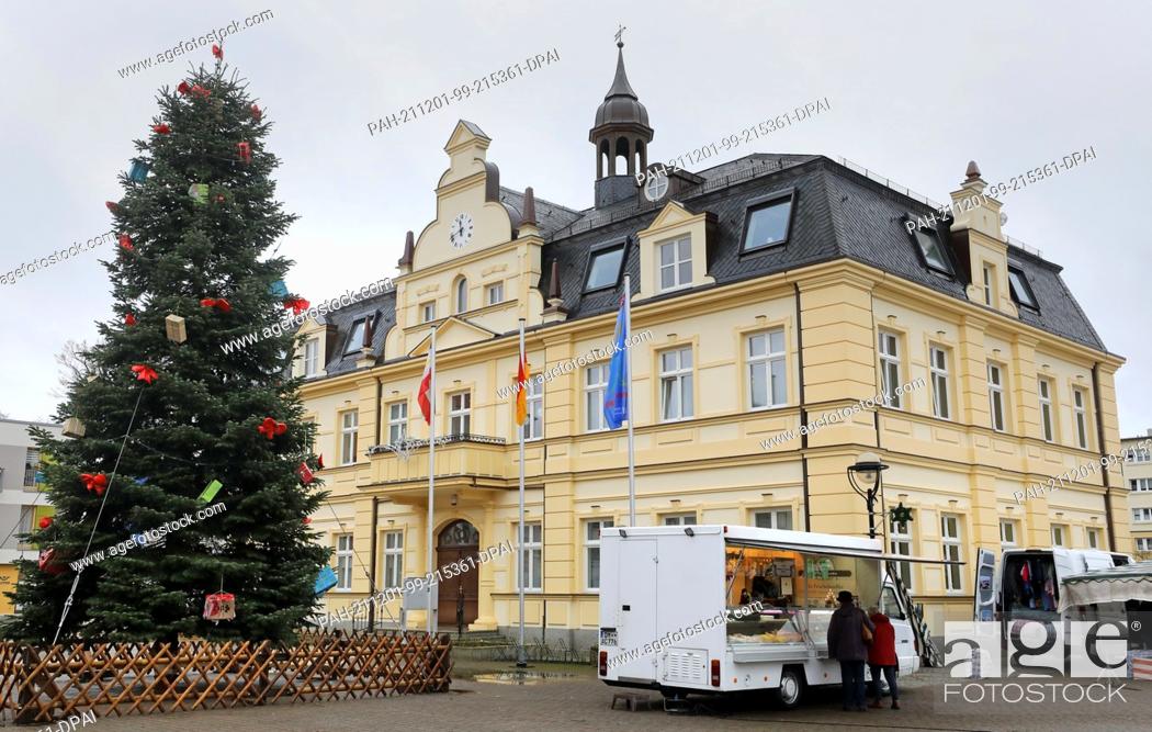 Stock Photo: 01 December 2021, Mecklenburg-Western Pomerania, Demmin: Next to the town hall on the market square is a large Christmas tree, as few people are out and about.