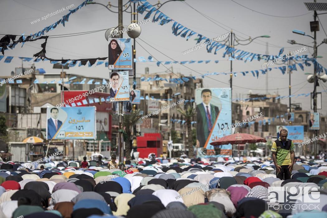Stock Photo: Iraqi men attend Friday prayers backdropped by campaign posters for the upcoming parliamentary elections in the Sadr City suburb of Baghdad, Iraq, 20 April 2018.