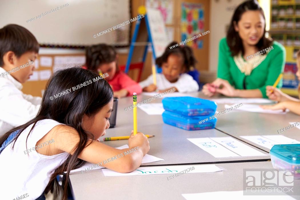 Stock Photo: Teacher sitting with kids in elementary school lesson.