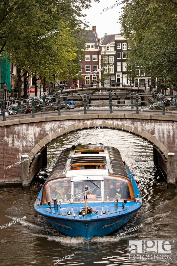 Stock Photo: A tour boat passes under the Hemonybrug bridge at Keizersgracht and Leidsegracht in Amsterdam.