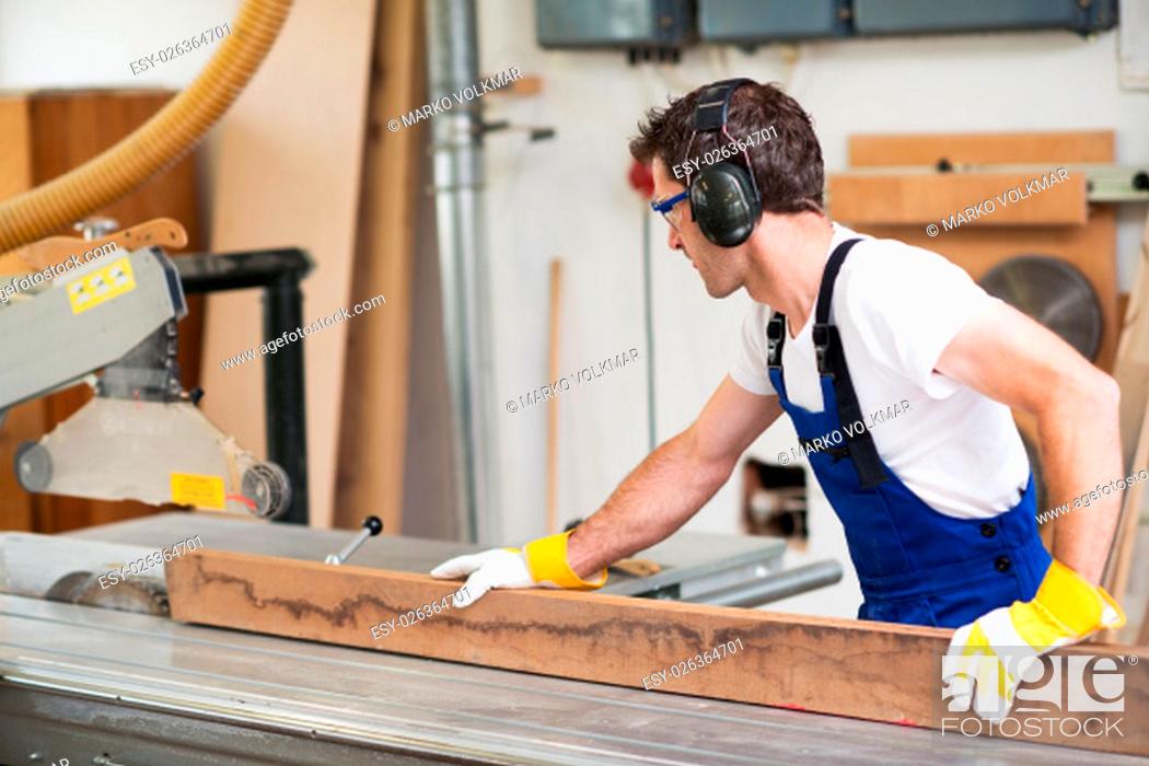 Stock Photo: worker in a carpenter's workshop using saw machine.