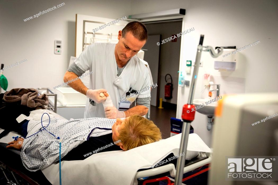 Stock Photo: Woman with broken wrist. The doctor reduces the fracture while the nurse places the plaster.