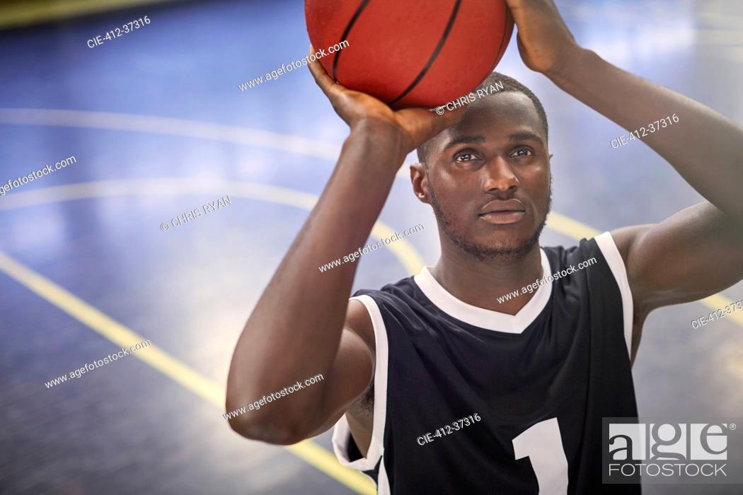 Stock Photo: Focused young male basketball player shooting the ball on court.