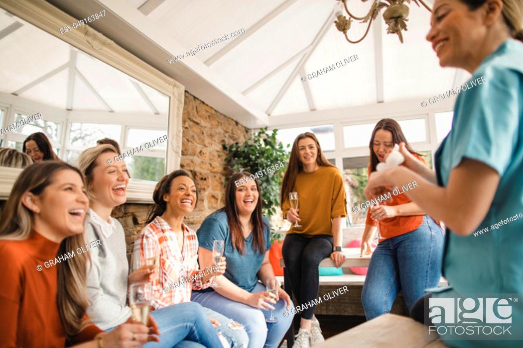 Stock Photo: Mid adult beauty sales representative making a sales pitch to a group of women at a product party.