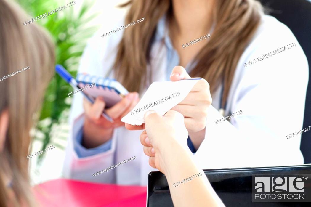 Stock Photo: Radiant female doctor giving a paper to her patient in her office.