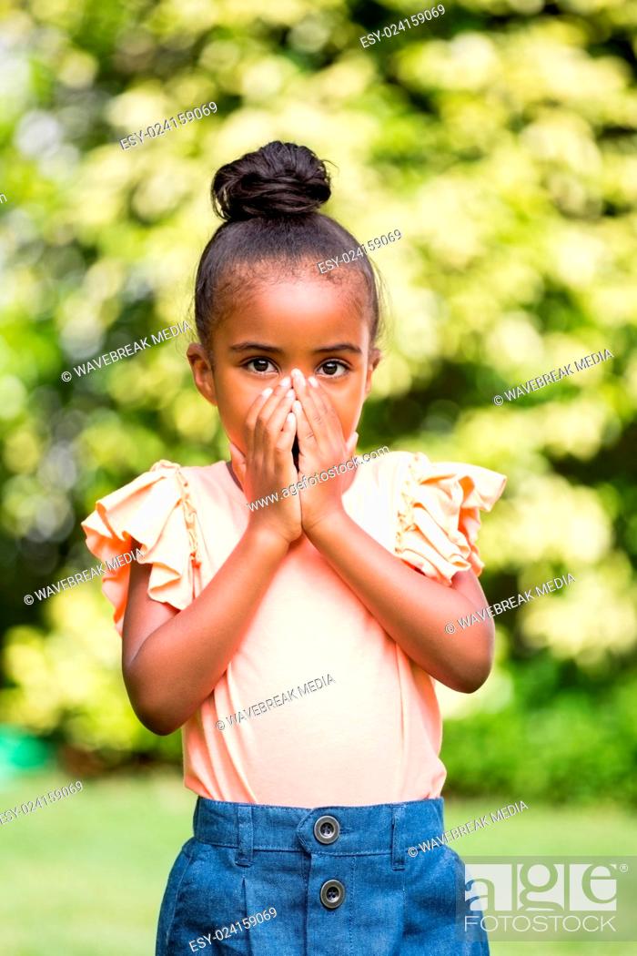 Stock Photo: Little girl hiding her mouth at park.