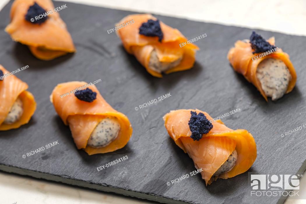 Stock Photo: smoked salmon rolls filled with cream cheese and black caviar.