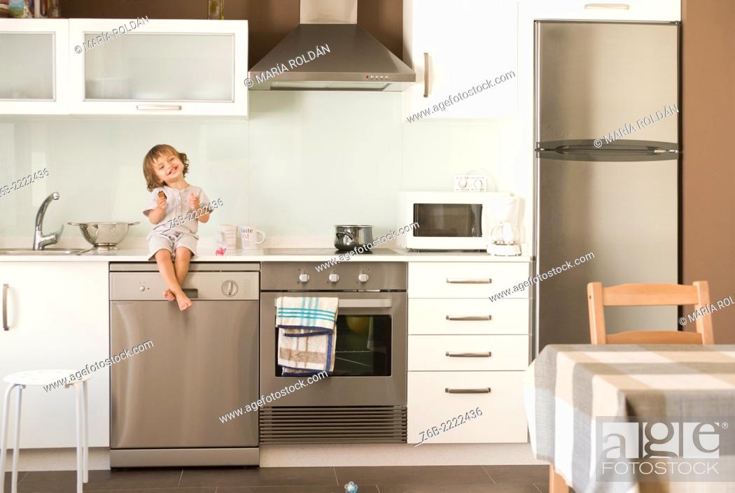 Stock Photo: 23 moths old baby girl seated on the counter top at the kitchen.