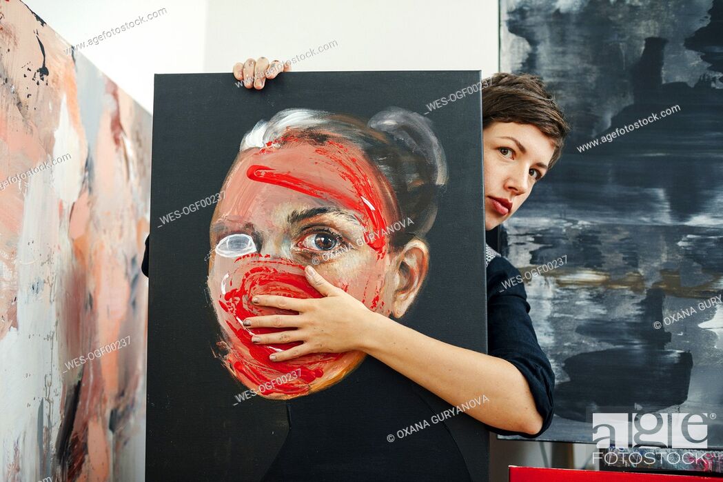 Stock Photo: Portrait of a female painter with painting in her studio.