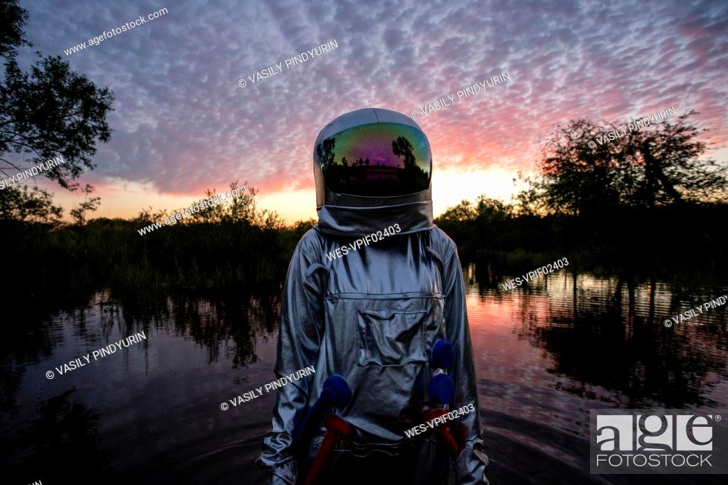 Stock Photo: Portrait of spacewoman standing in water at sunset.