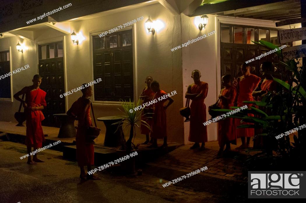 Stock Photo: Buddhist monks gathering to receive alms in the early morning before sunrise from the people of the UNESCO world heritage town of Luang Prabang in Central Laos.