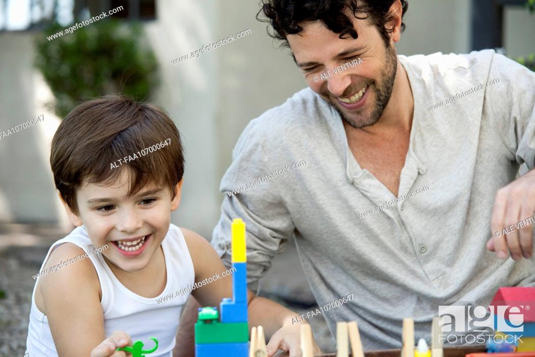 Stock Photo: Father and son laughing while playing with toys.