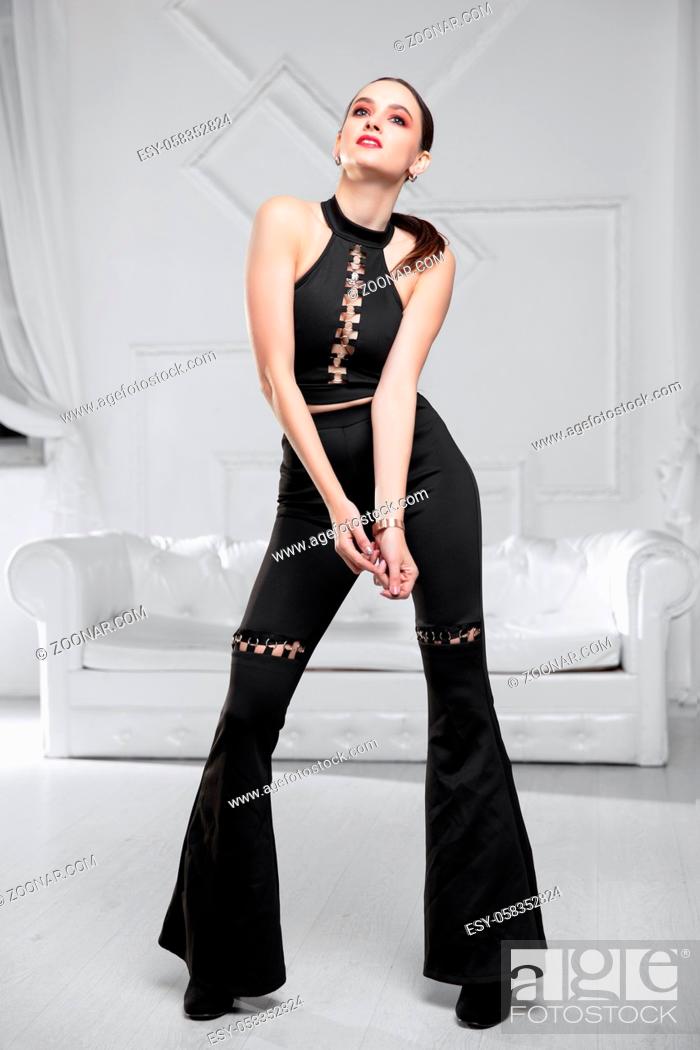 Stock Photo: Sexy brunette dressed in a black bustier and pants posing in the studio.