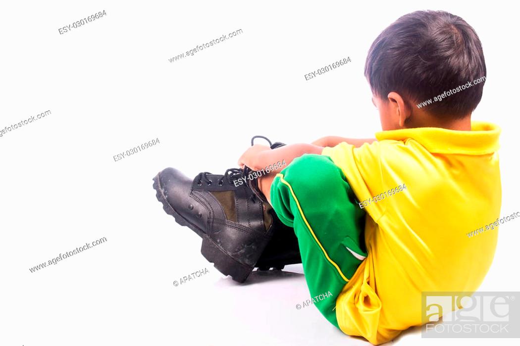 Stock Photo: little boy try wearing big shoe, focus shoe.