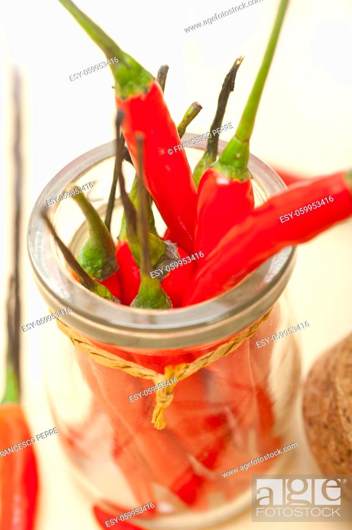 Imagen: red chili peppers on a glass jar over white wood rustic table.