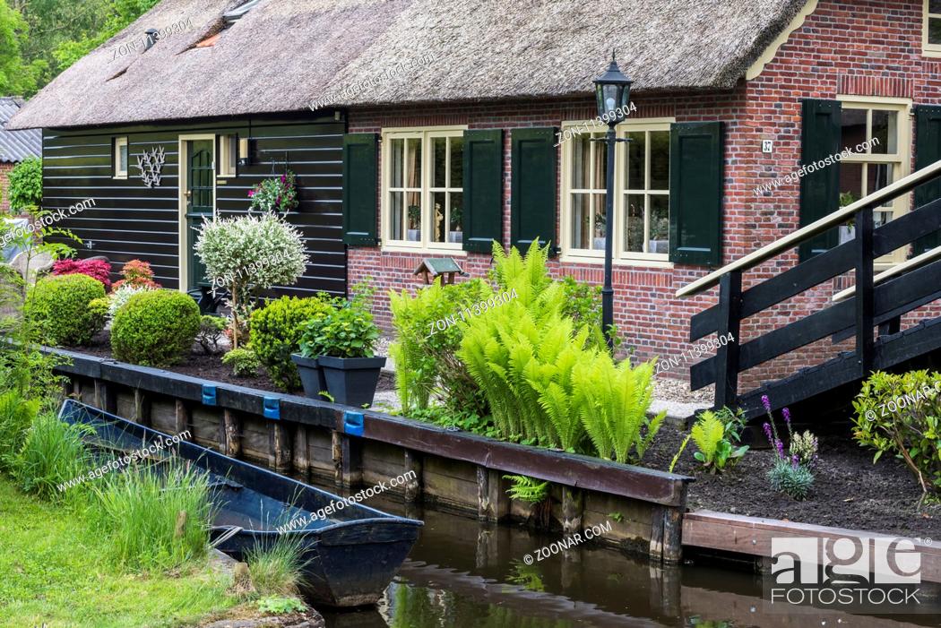 Stock Photo: Giethoorn, The Netherlands - May 19., 2016: Front of a monumental house in the small, picturesque town of Giethoorn with canal and rowing boat, Overijssel.