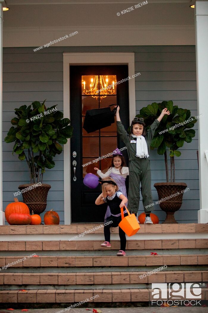 Stock Photo: Boy and sisters trick or treating celebrating on porch.