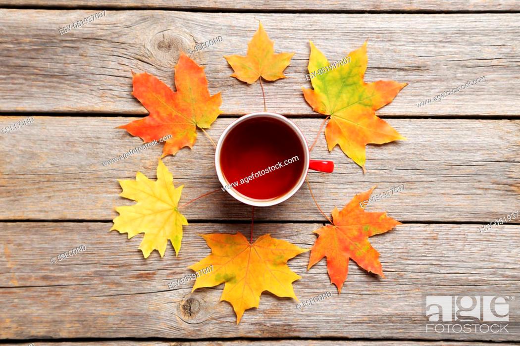 Imagen: Autumn leafs with cup of tea on grey wooden table.