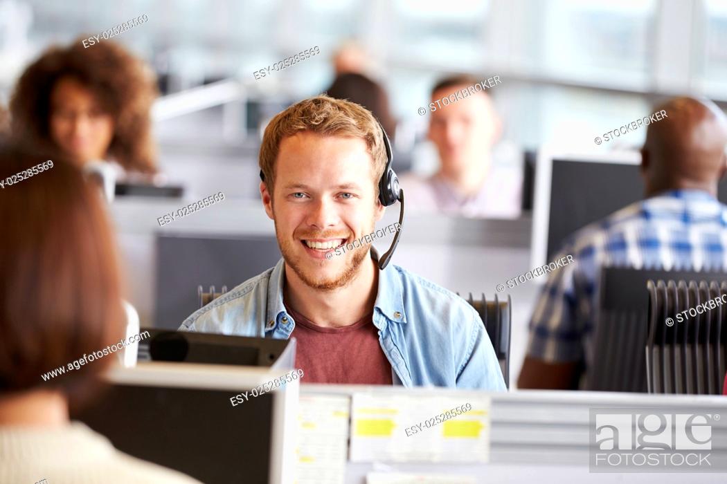 Stock Photo: Young man working in a call centre, looking to camera.