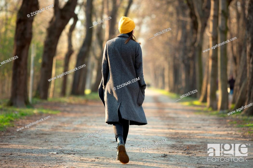 Stock Photo: Rear view of a young woman walking on an avenue . Travel and fashion concept.