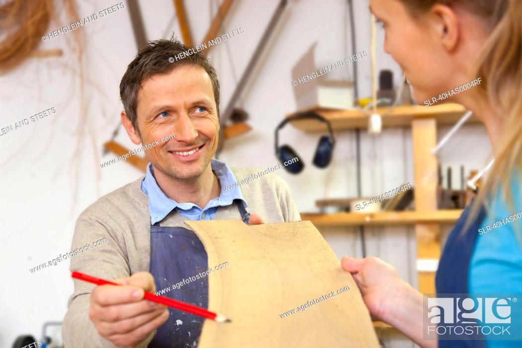 Stock Photo: Carpenter giving blueprints to assistant.