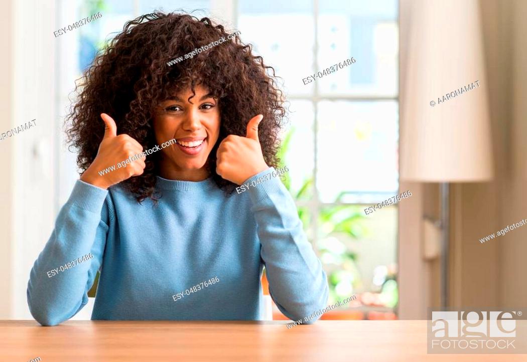 Stock Photo: African american woman at home success sign doing positive gesture with hand, thumbs up smiling and happy. Looking at the camera with cheerful expression.