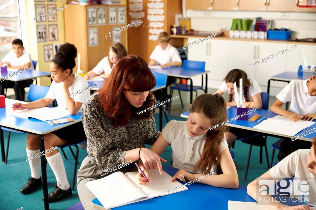 Stock Photo: Teacher helping a girl with work at her desk, elevated view.