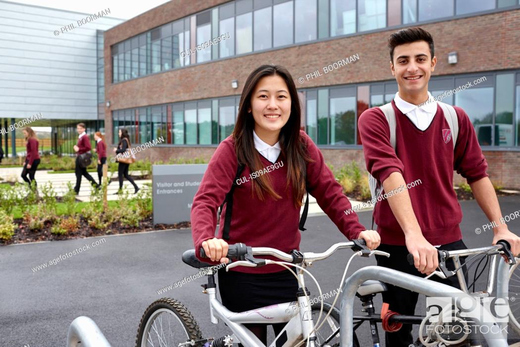 Stock Photo: Teenager friends with cycles outside school.