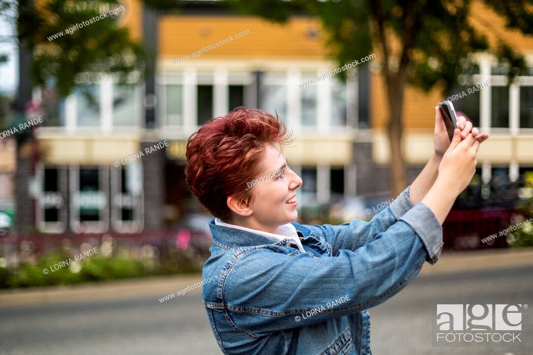 Stock Photo: A teenage girl with red hair taking a self-portrait with a smart phone; Abbotsford, British Columbia, Canada.
