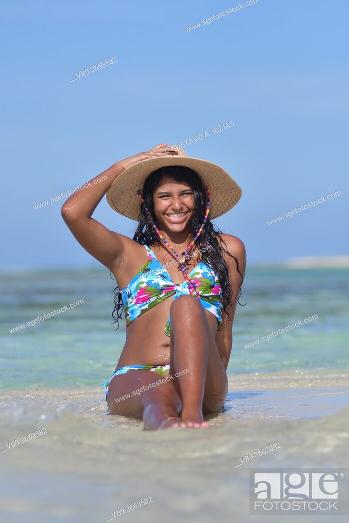 Hispanic Woman siting on a beach wearing a and straw hat look at camera, Foto de Stock, Imagen Protegidos Pic. VB9-3663582 | agefotostock