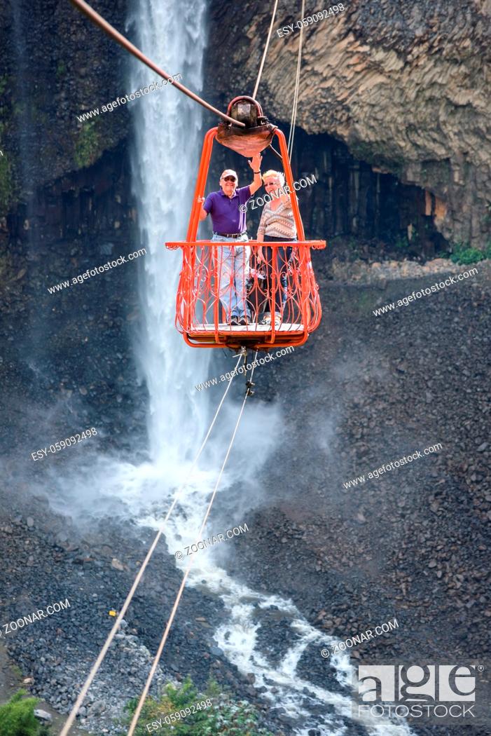 Stock Photo: Ecuador, Tunguragua - November 27, 2017: Senior tourists gliding on the zip line trip against Bridal veil (Manto de la novia), waterfall in Cascades route.