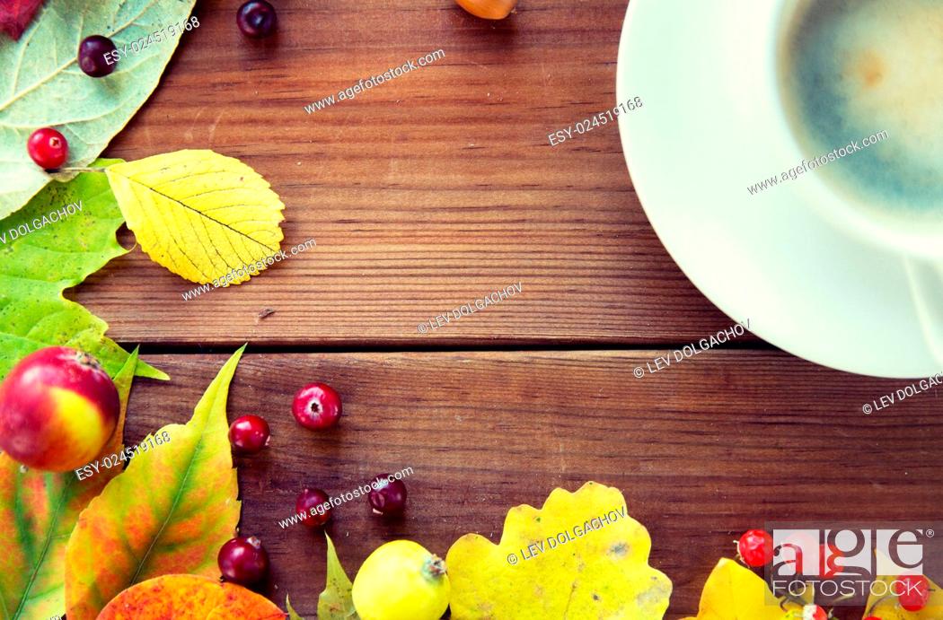 Stock Photo: season, drink and morning concept - close up of coffee cup on wooden table with autumn leaves.