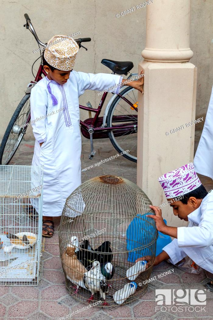 Stock Photo: An Omani Boy Sells Exotic Birds At The Friday Bird Market, Nizwa, Ad Dakhiliyah Region, Oman.