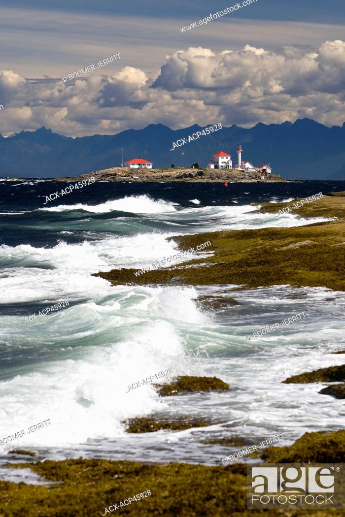 Stock Photo: The lighthouse on Entrance Island stands out against a mountainous west coast backdrop amid a crashing surf onto Gabriola Island, Southern Gulf Islands.